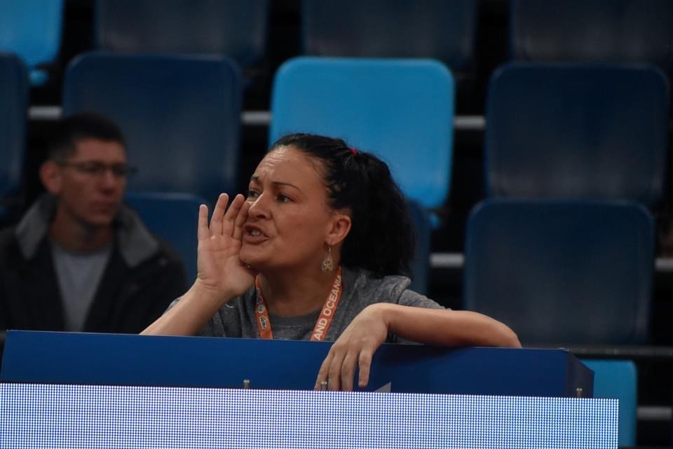Carrie Chandler actively coaching from the competition floor while leaning over the barrier.