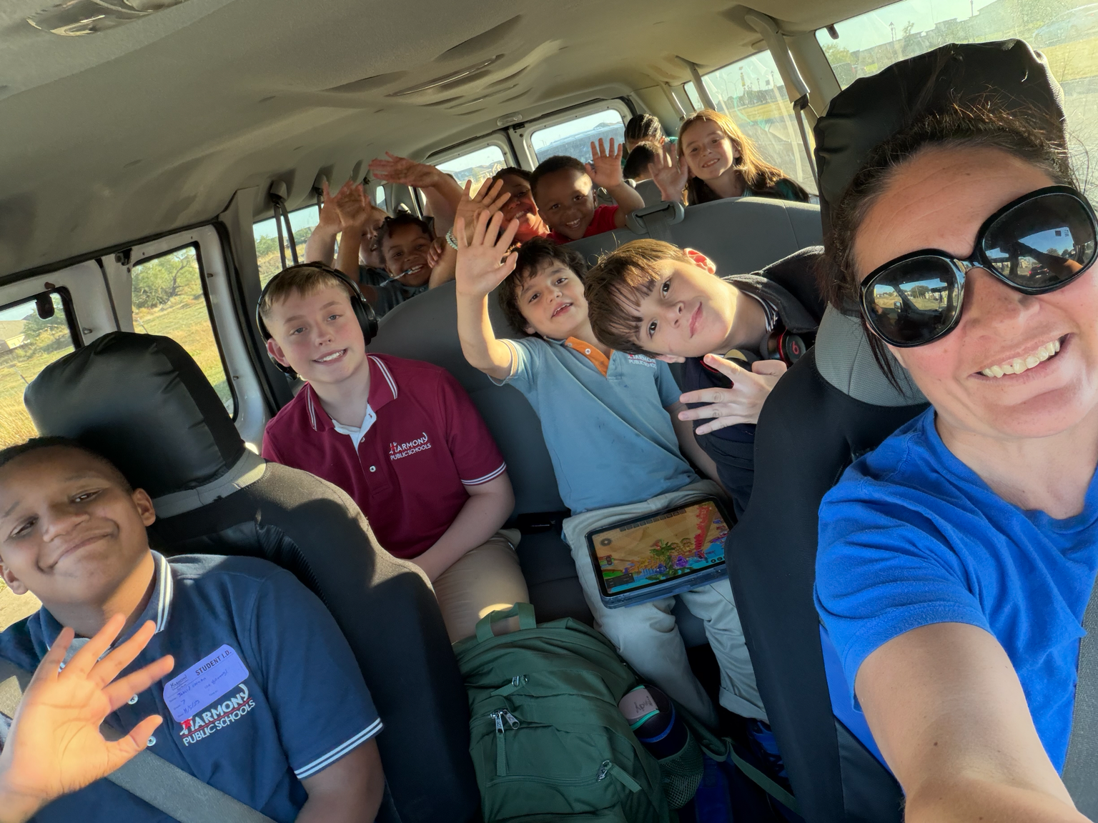 Carrie Chandler driving the program van while children seated safely behind her smile and wave at the camera.
